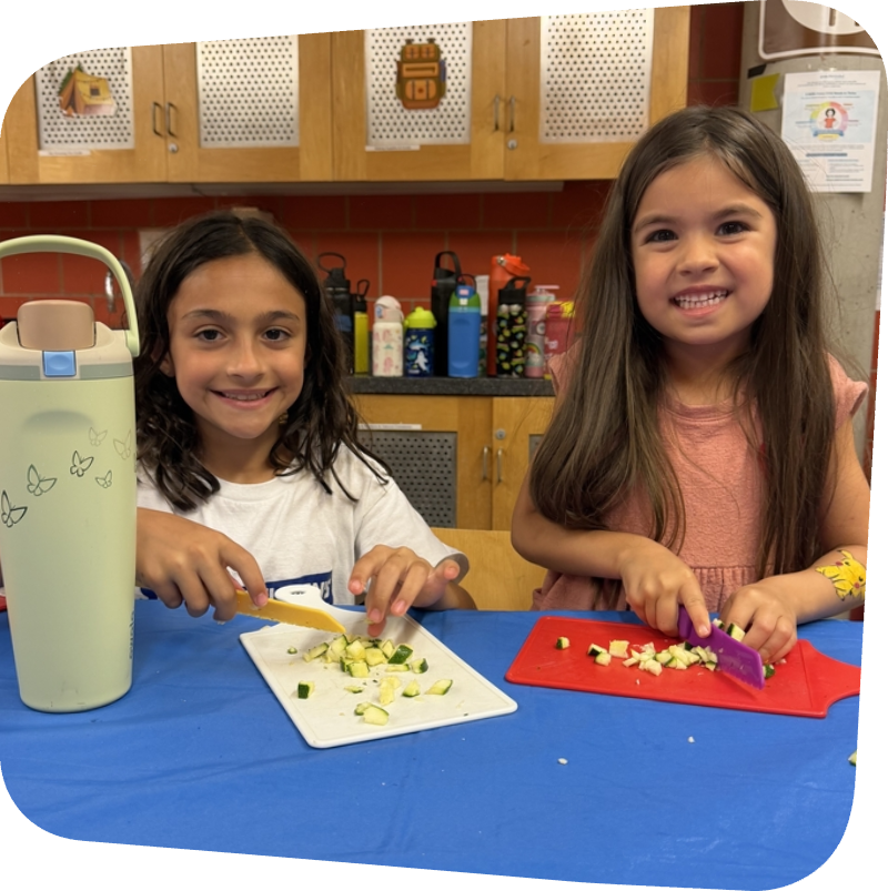 two girls cutting veggies in cooking class at the Staten Island Children's Museum