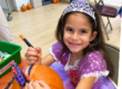 smiling girl decorating a pumpkin at the Staten Island Children's Museum halloween party