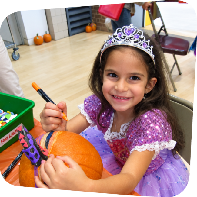 oct pr rhombus 2 smiling girl decorating a pumpkin at the Staten Island Children's Museum halloween party