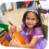 smiling girl decorating a pumpkin at the Staten Island Children's Museum halloween party