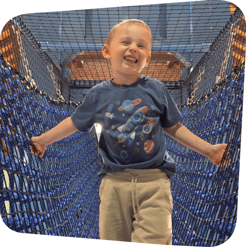 smiling boy on the rope bridge in the Explore Staten Island exhibit at the Staten Island Children's Museum