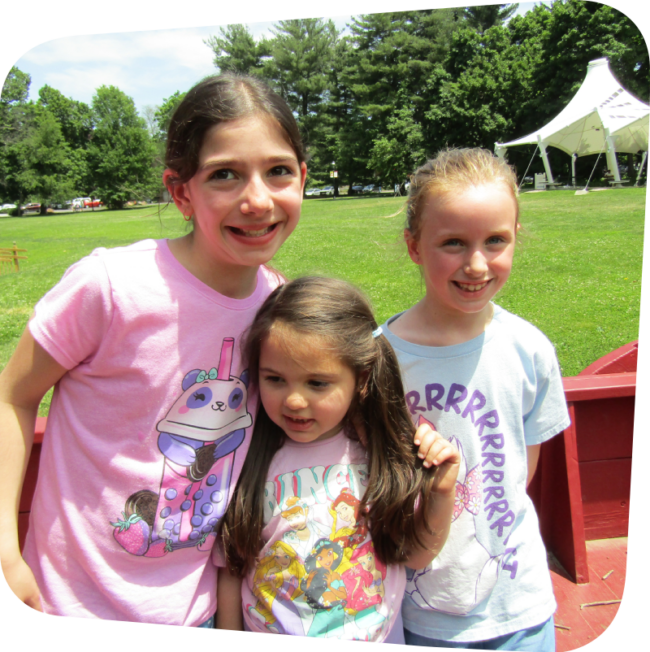 three girls in the wagon on the meadow at the Staten Island Children's Museum